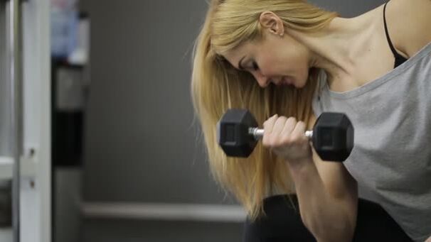 The girl performs an exercise for dumbbells